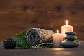 Spa setting with candles, hot stones, and towel